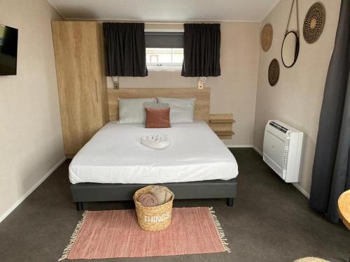 een slaapkamer met een groot bed met een mand erop bij Vakantiepark de Meerpaal in Zoutelande