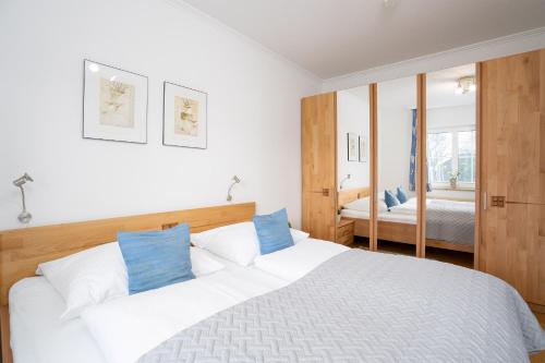 ein Schlafzimmer mit einem großen weißen Bett mit blauen Kissen in der Unterkunft Seepark Wohnung 2 1 in Scharbeutz