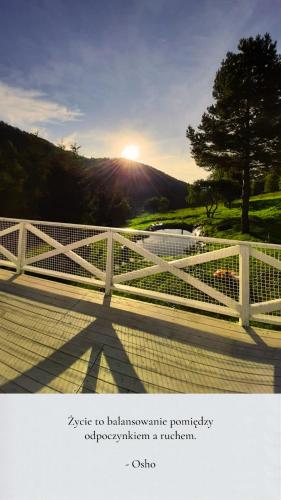 einen weißen Zaun mit der Sonne im Hintergrund in der Unterkunft Poza Czasem in Bystrzyca Kłodzka