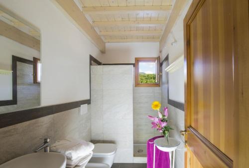 baño con lavabo, aseo y un jarrón de flores en Il Fienile di Margherita, en Vicchio