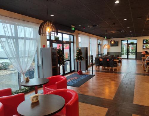 a lobby with red chairs and tables in a restaurant at Hotel Picaro Kraśnik Dolny in Bolesławiec