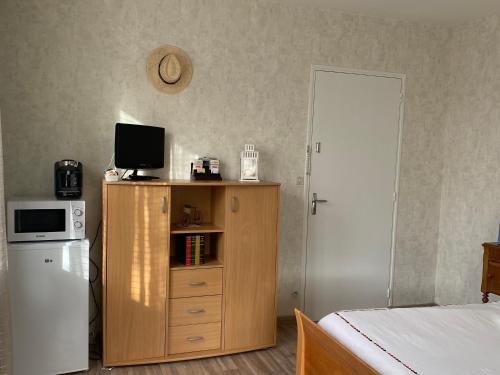 um quarto com uma cama e uma cómoda com uma televisão em Chambre au bruand em Saint-Porchaire