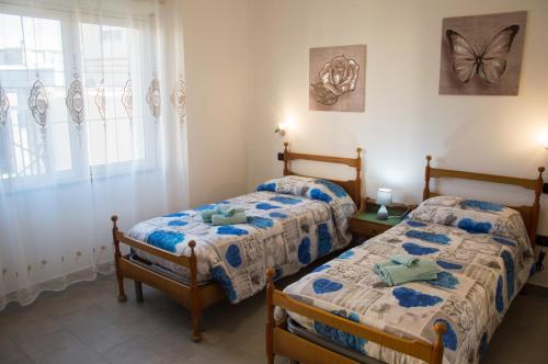 2 Betten in einem Zimmer mit einem Schmetterling an der Wand in der Unterkunft Casa jole in Assemini