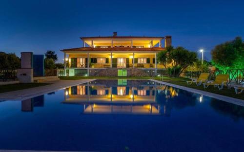 une grande maison avec une piscine en face de celle-ci dans l'établissement Quinta Do Ribeirinho, à Vilar da Mó