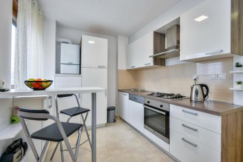 a kitchen with white cabinets and a table and chairs at Florek & Florica Apartment in Križevci