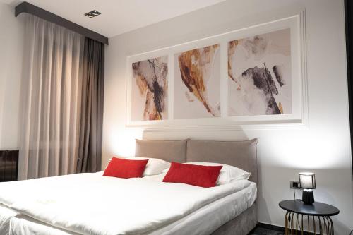 a bedroom with a bed with two red pillows at SAVOY residence in Osijek
