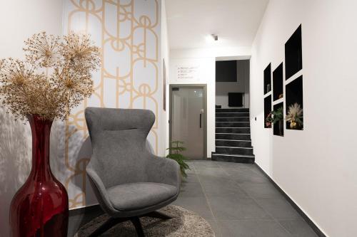 a living room with a chair and a vase with flowers at SAVOY residence in Osijek