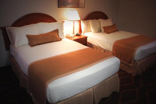 a hotel room with two beds and a lamp at Ramada by Wyndham Medicine Hat in Medicine Hat