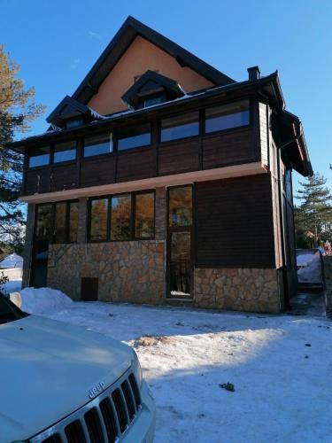 a house with snow on the ground in front of it at Tara Bozic Apartmani in Kaludjerske Bare