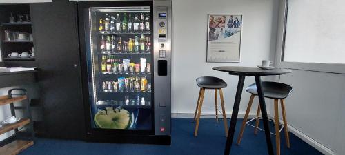 a drink cooler with two bar stools and a table at Comfort Hotel Atlantic Muenchen Sued in Ottobrunn