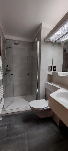 a bathroom with a shower and a toilet and a sink at Comfort Hotel Atlantic Muenchen Sued in Ottobrunn