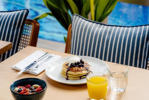 a plate of pancakes and a bowl of fruit on a table at Virgin Hotels London - Shoreditch in London