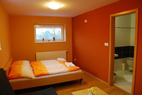 Schlafzimmer mit orangefarbenen Wänden, einem Bett und einem Fenster in der Unterkunft Vinařství Novotný in Čejkovice