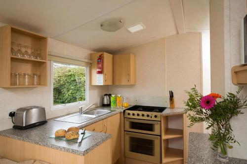 a kitchen with a sink and a stove top oven at Whitecliff Bay Holiday Park in Bembridge