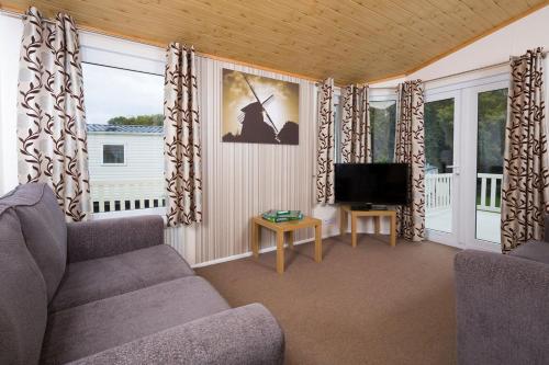 a living room with a couch and a television at Whitecliff Bay Holiday Park in Bembridge