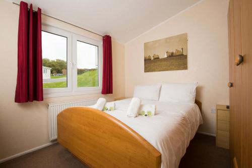 a bedroom with a bed with two teddy bears on it at Whitecliff Bay Holiday Park in Bembridge
