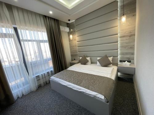 a bedroom with a bed and a large window at Terrasse Hotel & Bar in Bishkek