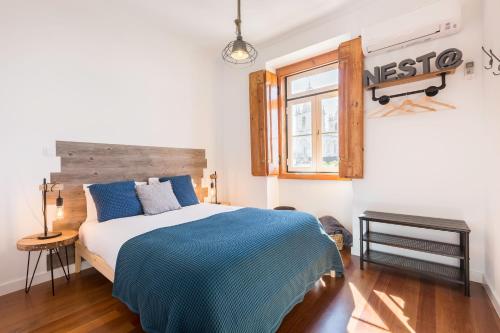 a bedroom with a bed with a blue blanket and a window at Graça and Alfama Heritage 3-BR Signature Suites by NestAtLisbon in Lisbon