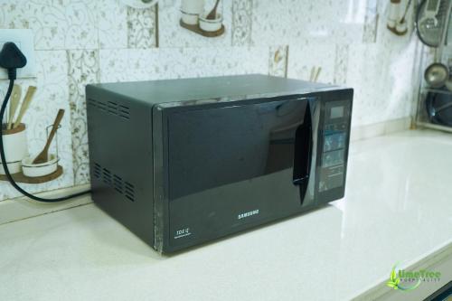 a black microwave sitting on top of a counter at Lime Tree Hotel Near 32nd Avenue Sector 29 Gurgaon in Gurgaon