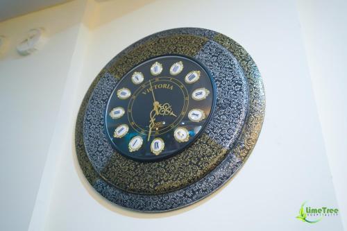 a black and gold clock on a plate on a wall at Lime Tree Hotel Near 32nd Avenue Sector 29 Gurgaon in Gurgaon