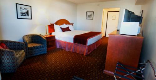 a hotel room with a bed and a chair at Ramada by Wyndham Medicine Hat in Medicine Hat