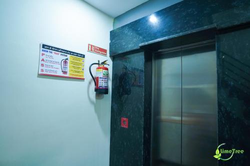 a bathroom with a fire extinguisher on the wall at Lime Tree Hotel Near 32nd Avenue Sector 29 Gurgaon in Gurgaon