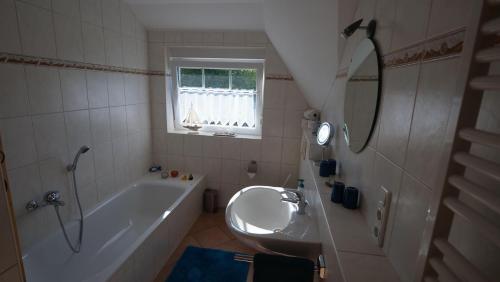 ein Badezimmer mit einer Badewanne, einem Waschbecken und einem Spiegel in der Unterkunft Ferienwohnung Amanda 1 in Bad Zwischenahn