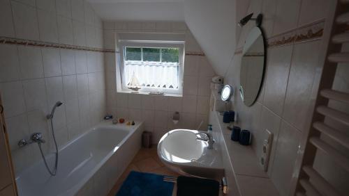 ein Badezimmer mit Badewanne, Waschbecken und Spiegel in der Unterkunft Ferienwohnung Amanda 1 in Bad Zwischenahn