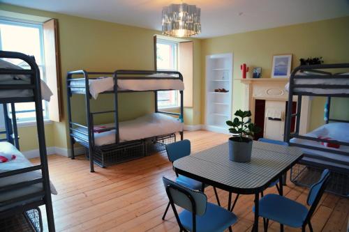 um quarto com uma mesa, cadeiras e beliches em The Dolphin Inn Hostel em Dunbar