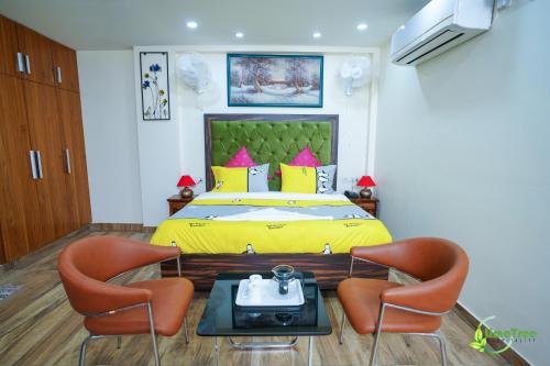 a bedroom with a yellow bed with two chairs at Lime Tree Hotel Near 32nd Avenue Sector 29 Gurgaon in Gurgaon