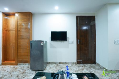 a room with a refrigerator and a tv on the wall at Lime Tree Hotel Near 32nd Avenue Sector 29 Gurgaon in Gurgaon