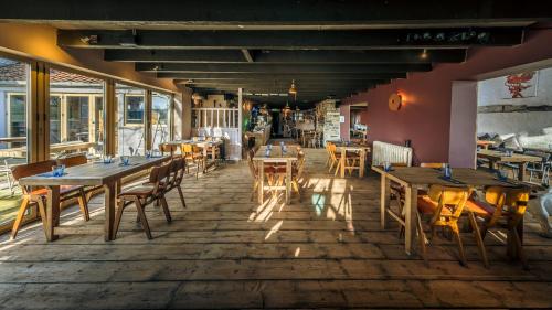 um restaurante com mesas e cadeiras de madeira e janelas em The Sheppey em Glastonbury