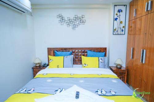 a bedroom with a bed with yellow and blue pillows at Lime Tree Hotel Near 32nd Avenue Sector 29 Gurgaon in Gurgaon