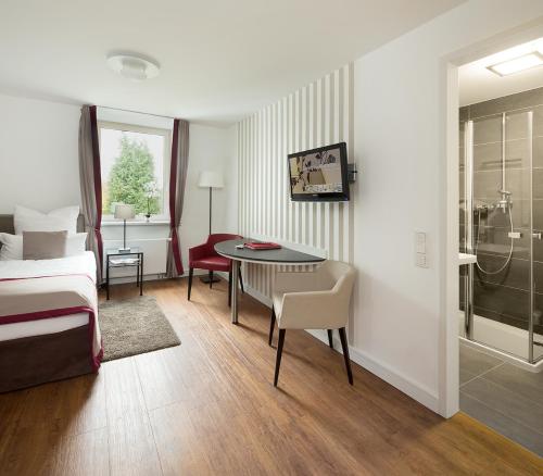 a hotel room with a bed and a table and chairs at Boardinghouse Rathsmühle in Aachen