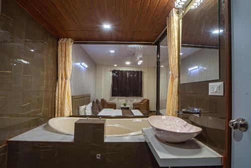 a bathroom with a bath tub and a sink at Hotel Jurkis, Kolhapur in Kolhapur