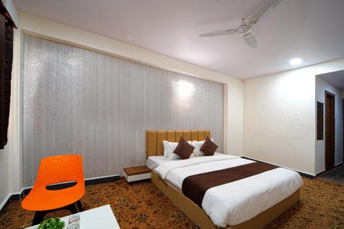 a bedroom with a large bed and a orange chair at Hotel Jurkis, Kolhapur in Kolhapur