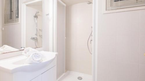 a white bathroom with a sink and a shower at 1Blan - Llafranc in Llafranc
