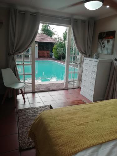 a bedroom with a bed and a view of a pool at 4 Michael Place in Edenvale