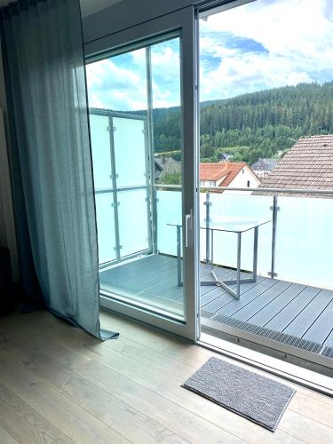 an open glass door with a balcony with a table at Exklusive 82 qm Loftwohnung mit Tiefgarage und Süd-Balkon zentral in Titisee-Neustadt