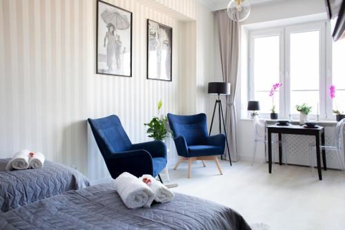 a bedroom with two beds and two chairs and a desk at Alton Aleje Apartment 3 in Warsaw