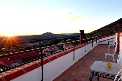 a balcony with a table and chairs and the sunset at Casal da Serra in Penha Garcia