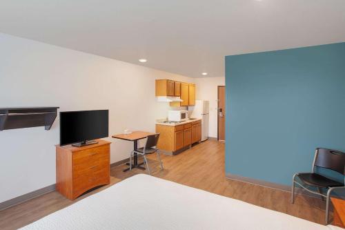 a living room with a television and a table with chairs at WoodSpring Suites Harlingen in Harlingen