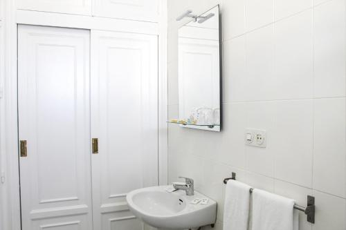 ein weißes Badezimmer mit einem Waschbecken und einem Spiegel in der Unterkunft VÍA SEVILLA - CÁDIZ Alojamiento & Restaurante in El Cuervo