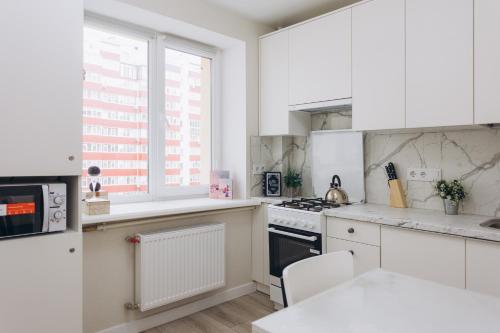 une cuisine avec des placards blancs et une fenêtre dans l'établissement Apart-smart 5.26 near Lavina 5 floor Kharkovskaya, à Soumy