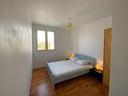 une chambre blanche avec un lit et une fenêtre dans l'établissement Appartement pour famille Saint-Pierre-la-Mer, à Fleury