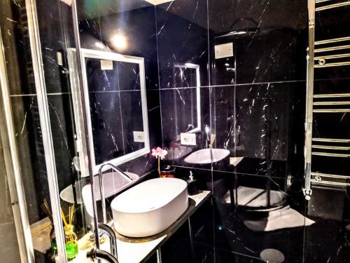 een zwart betegelde badkamer met een toilet en een wastafel bij NIK Rooms in Rome