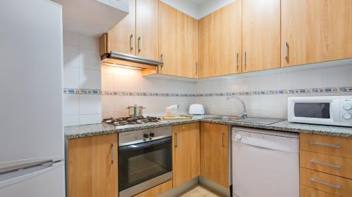 a kitchen with wooden cabinets and a microwave at 1 Bon Pl - Llafranc in Llafranc