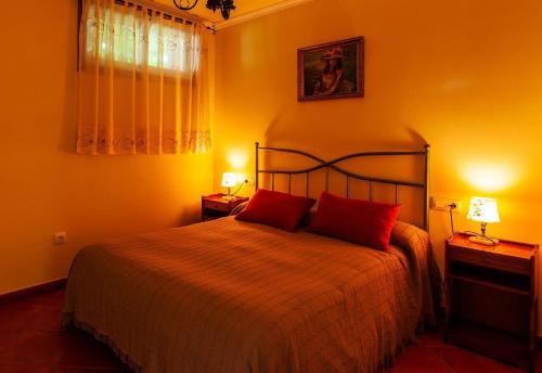 a bedroom with a bed with red pillows and two lamps at Apartamento con jardin en un chale in Bueu