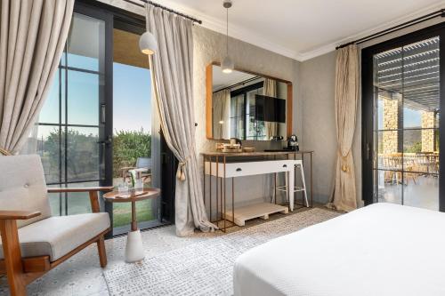 a bedroom with a bed and a chair and a mirror at Alacatı Port Ladera Hotel - Adult Only in Alaçatı