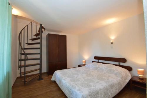 a bedroom with a bed and a spiral staircase at House Adriatic in Cunski